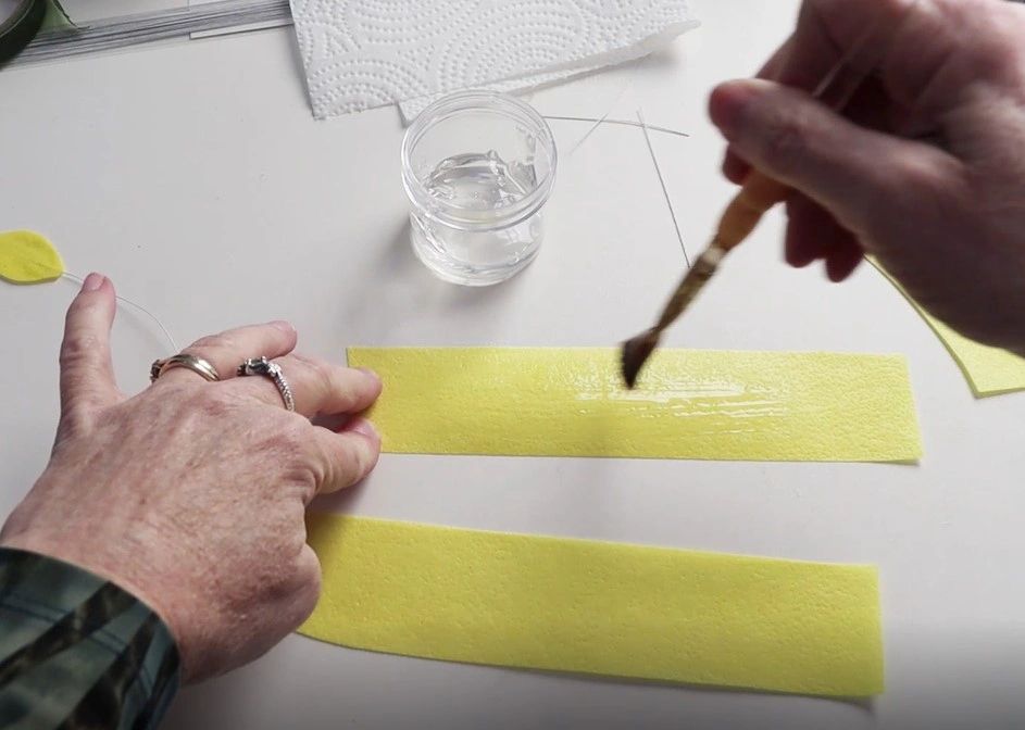 Add edible glue to one strip of yellow wafer paper. Add edible glue to one strip of yellow wafer paper.