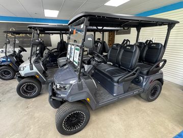 Gray golf cart with black seats and roof in a showroom.