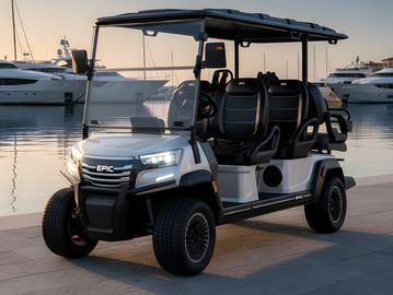 White, six-seat golf cart parked near marina at sunset.