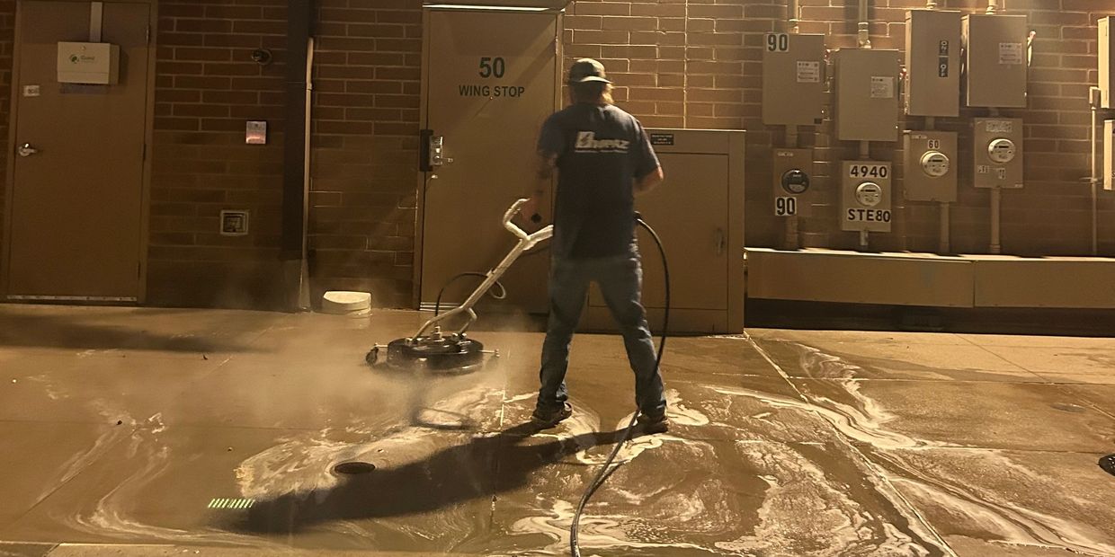 Man power washing in front of building
