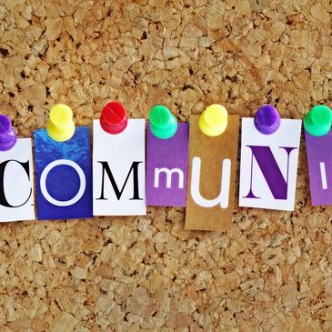 Colorful letters pinned on corkboard spelling 'community'.