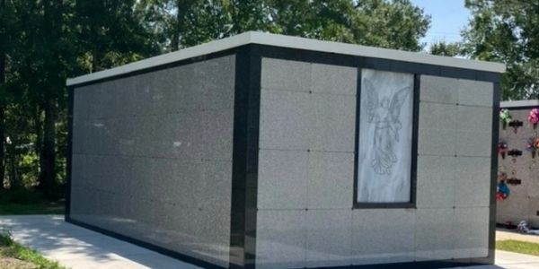 A modern mausoleum with a marble angel engraving on its side wall.