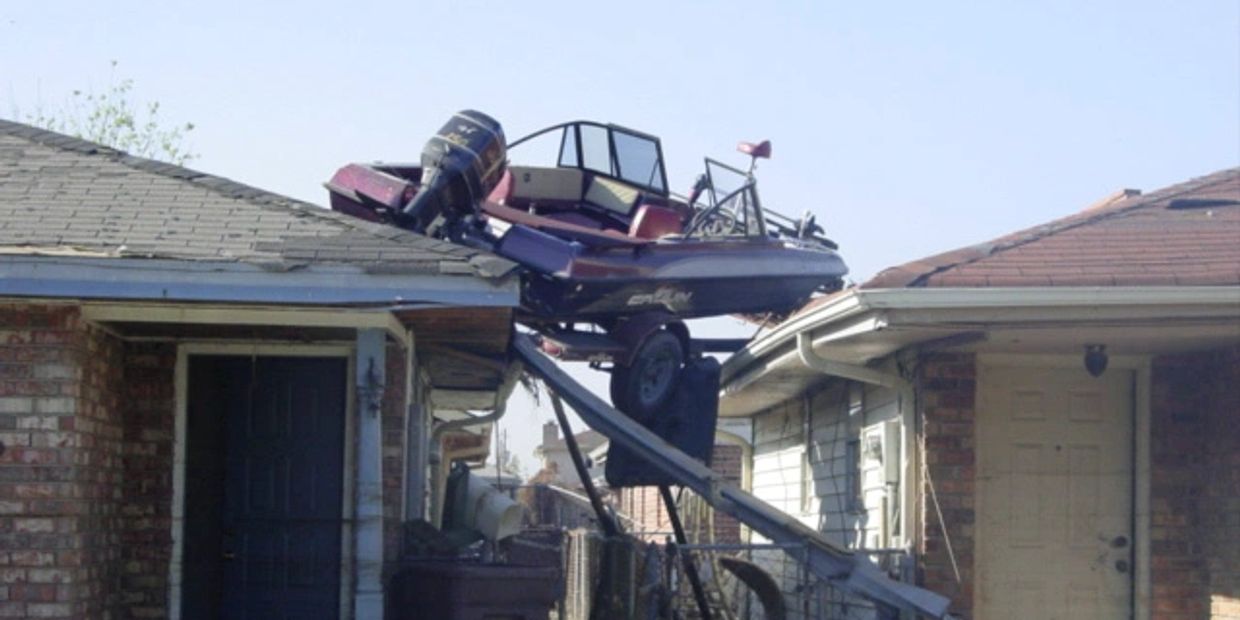 Boat accidentally lodged on rooftops of two houses.
