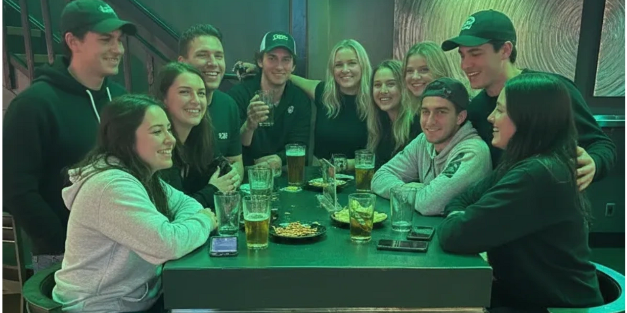A group of friends enjoying drinks and snacks at a bar table, smiling and having fun.