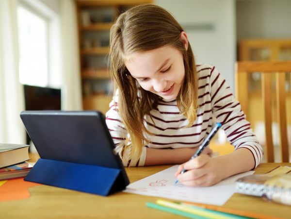 A young girl doing her homework with an online teacher