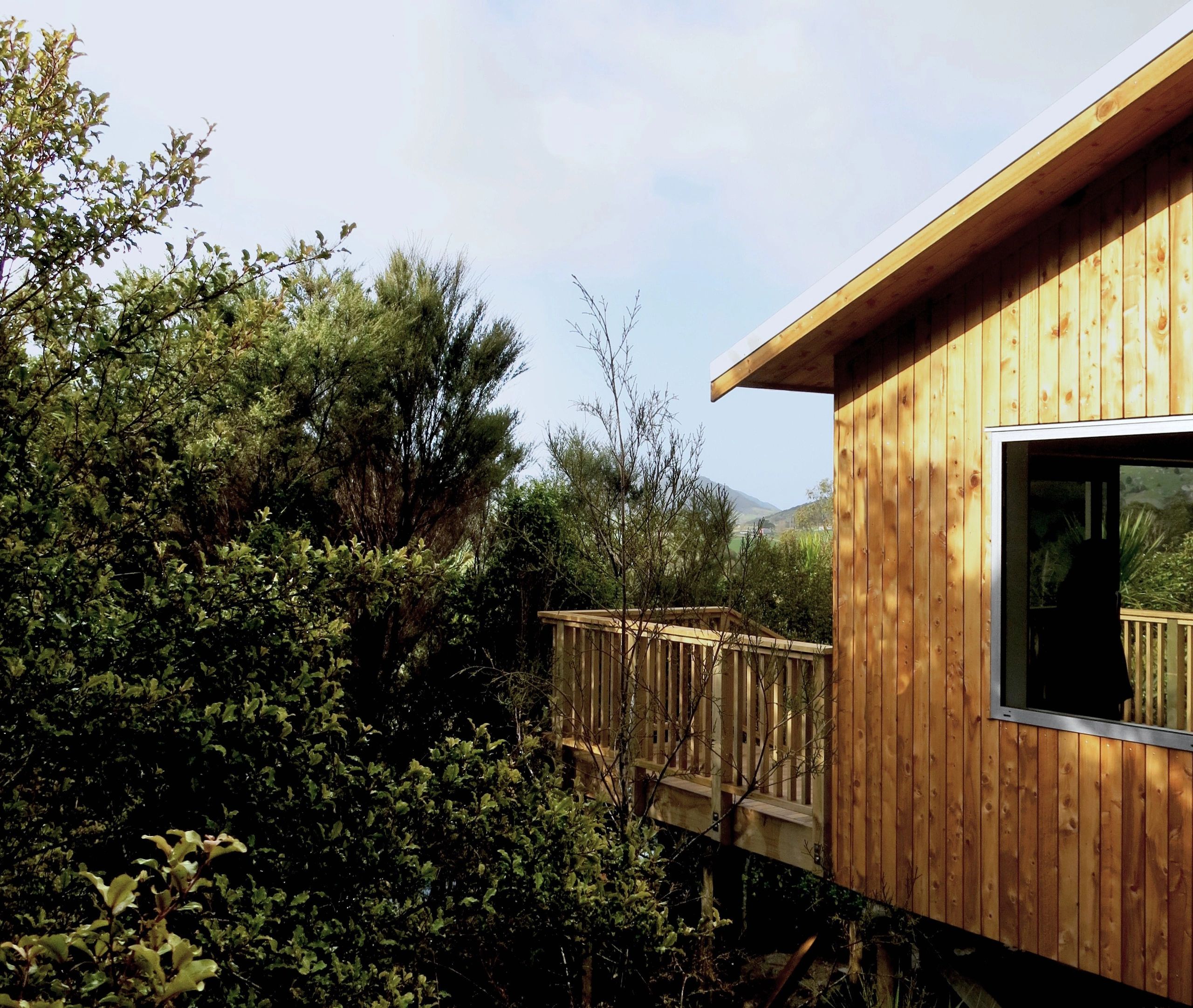 Wooden cabin surrounded by lush green trees under a bright sky.