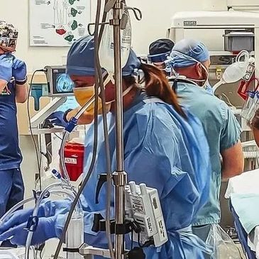 Medical team in protective gear performing a hospital procedure.
