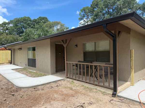 Small house with a porch and outdoor chairs.