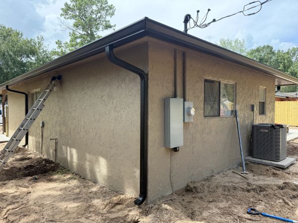 Side view of a stucco house with air conditioner and ladder.