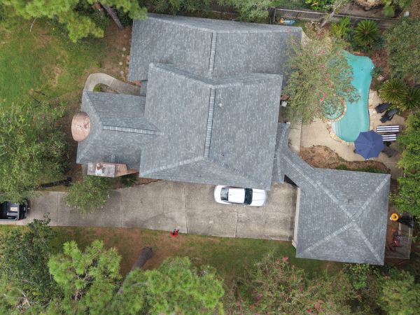 Aerial view of a house with a driveway, car, and swimming pool.