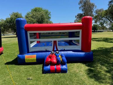 Inflatable boxing ring with gloves on the grass in a park.
