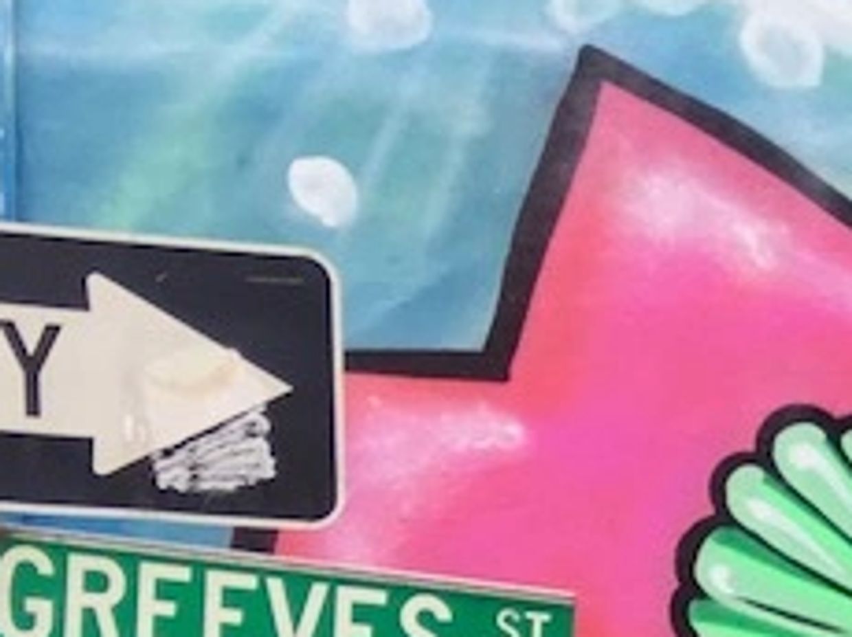 Tanda jalan dan mural warna-warni.