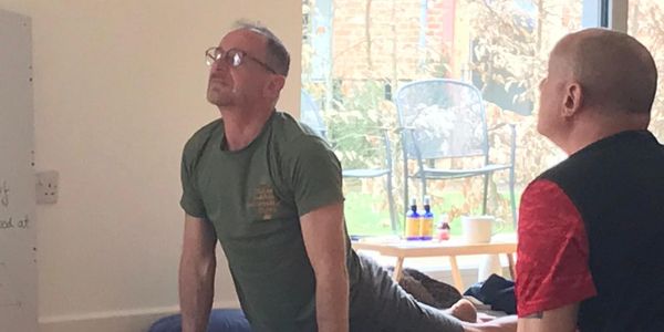 Two men practicing yoga indoors near a window.