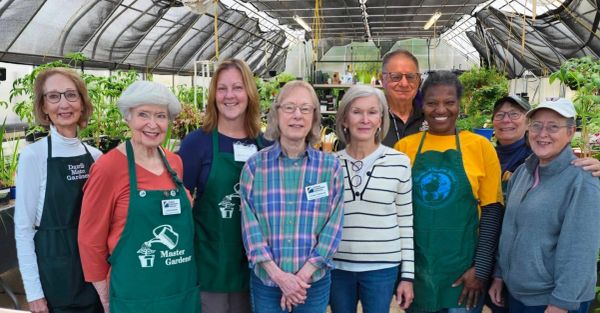Group of gardeners in a greenhouse smiling.