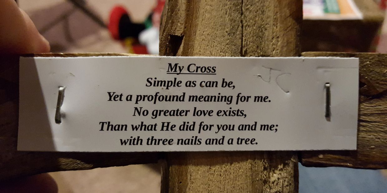 A wooden cross with a heartfelt poem about love and sacrifice attached.