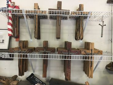 Wooden crosses with large nails displayed on a white wire shelf.