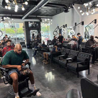Busy modern barbershop with customers and barbers at work.