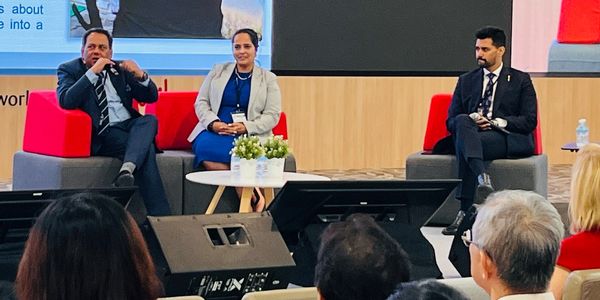 Three professionals seated on stage participating in a panel discussion.