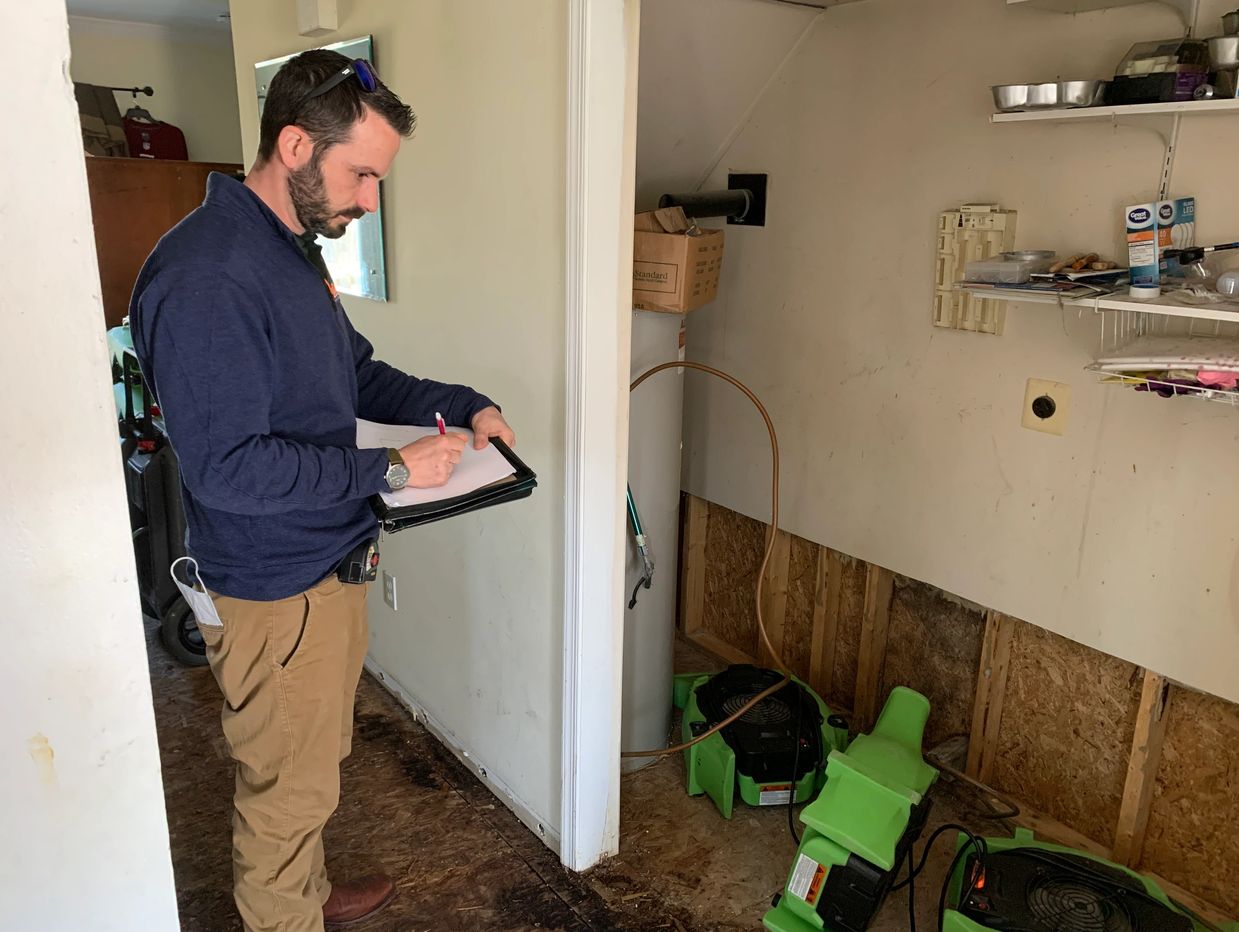 Man inspecting damage in a room, taking notes.