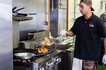 A Man Working On Food By A Stove