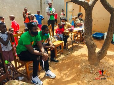 People gathered outdoors near a tree in a community setting.