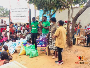Community members gathered for a donation event under a tree.