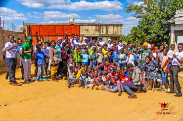 Large group of people posing outdoors on a sunny day.