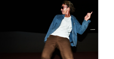 A man with momentum flying down the street on a skateboard