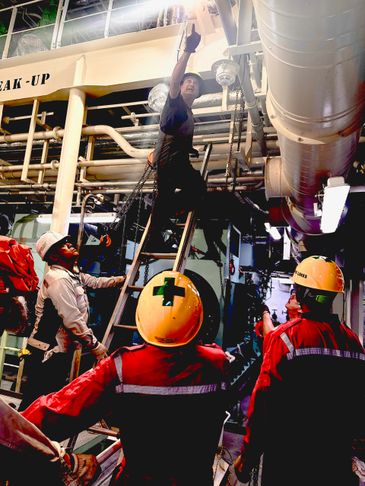 Workers in safety gear performing maintenance on industrial pipes.