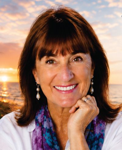Smiling woman with pearl earrings at sunset.