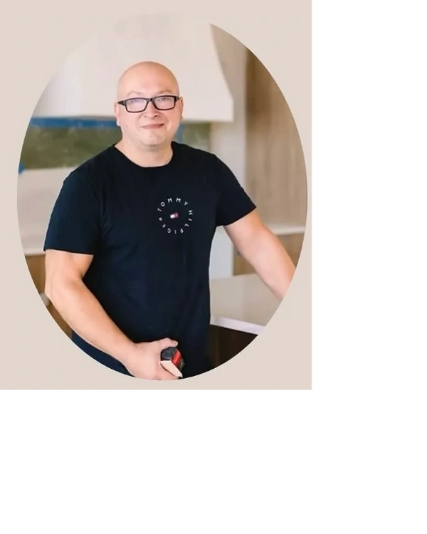 Man wearing glasses and a black Tommy Hilfiger t-shirt standing indoors.