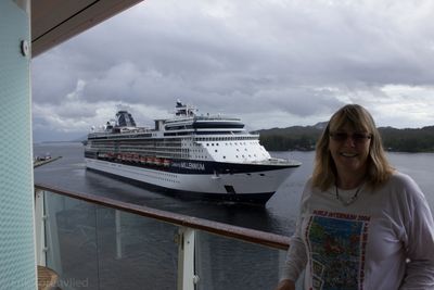 Cruise ship docked near a smiling woman on a balcony.