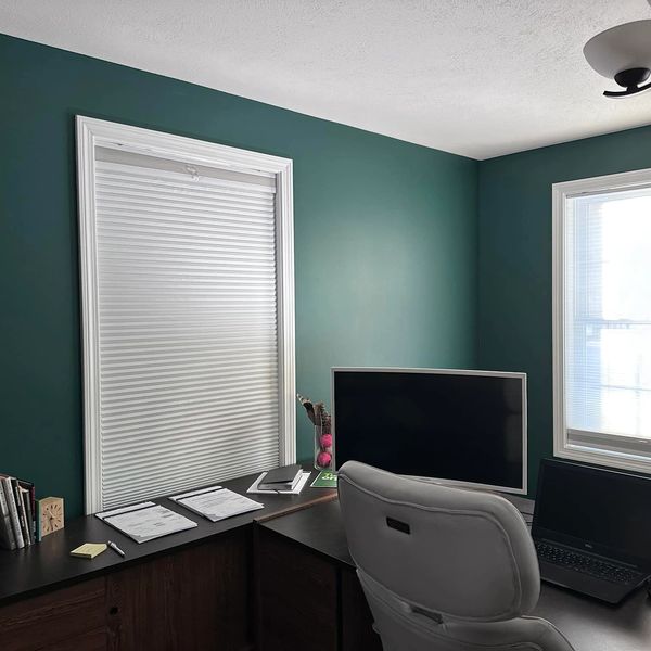 Home office with dark green walls, dual monitors, and a gray chair.
