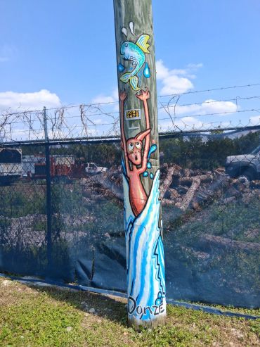 Colorful mural of a person catching a fish on a utility pole.