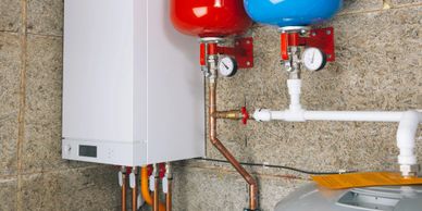 Wall-mounted boiler system with pipes and pressure gauges in a utility room.