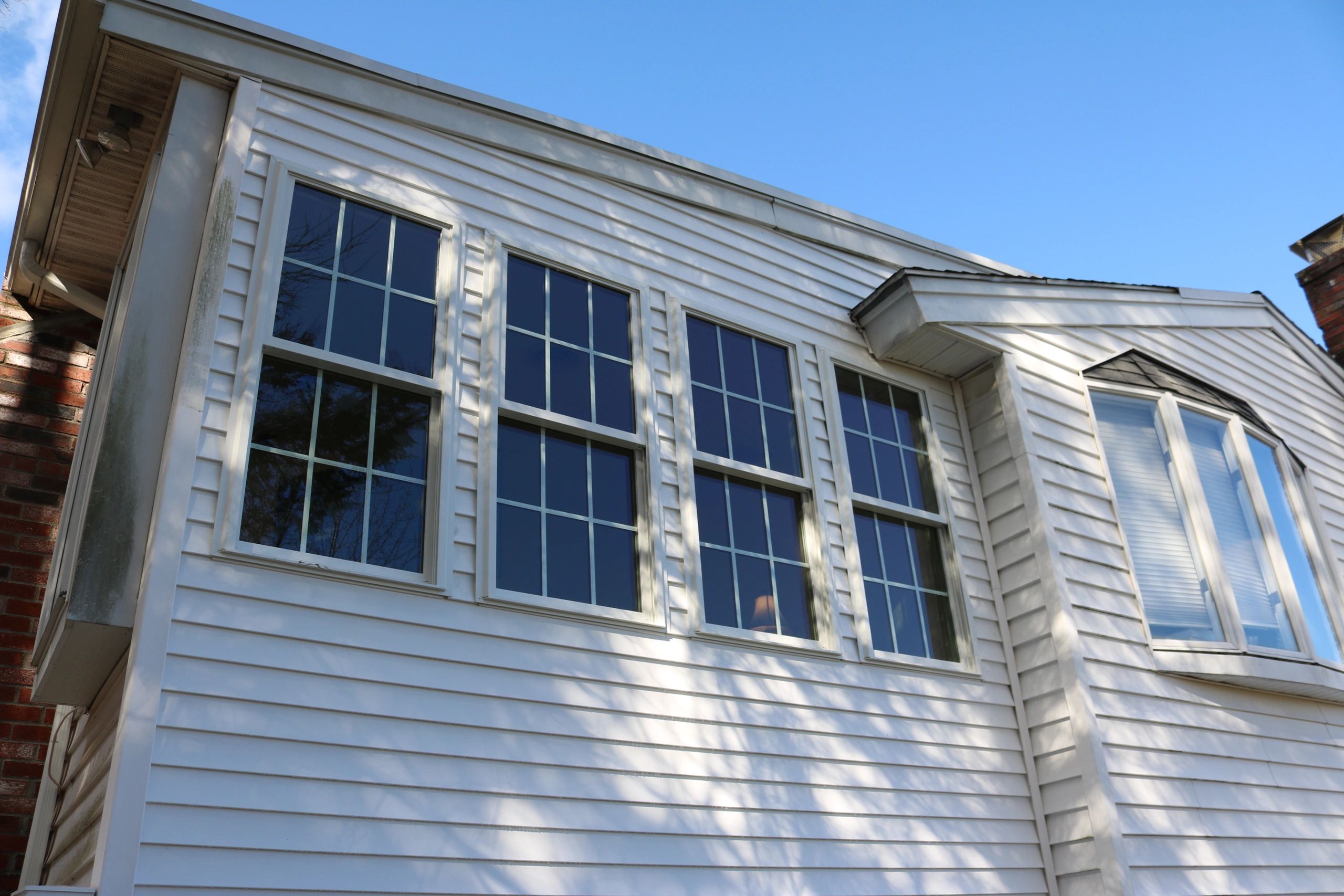 Exterior view of a white house with multiple large windows and clear blue sky.