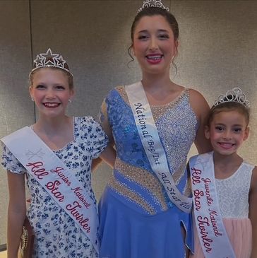 Three young beauty pageant winners smiling with tiaras and sashes.