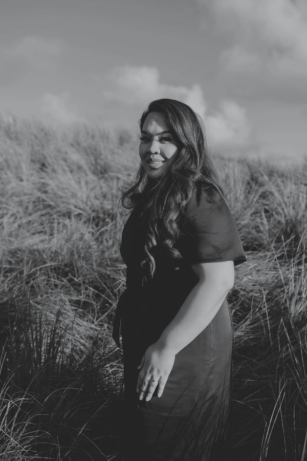 Woman in black dress standing in tall grass.