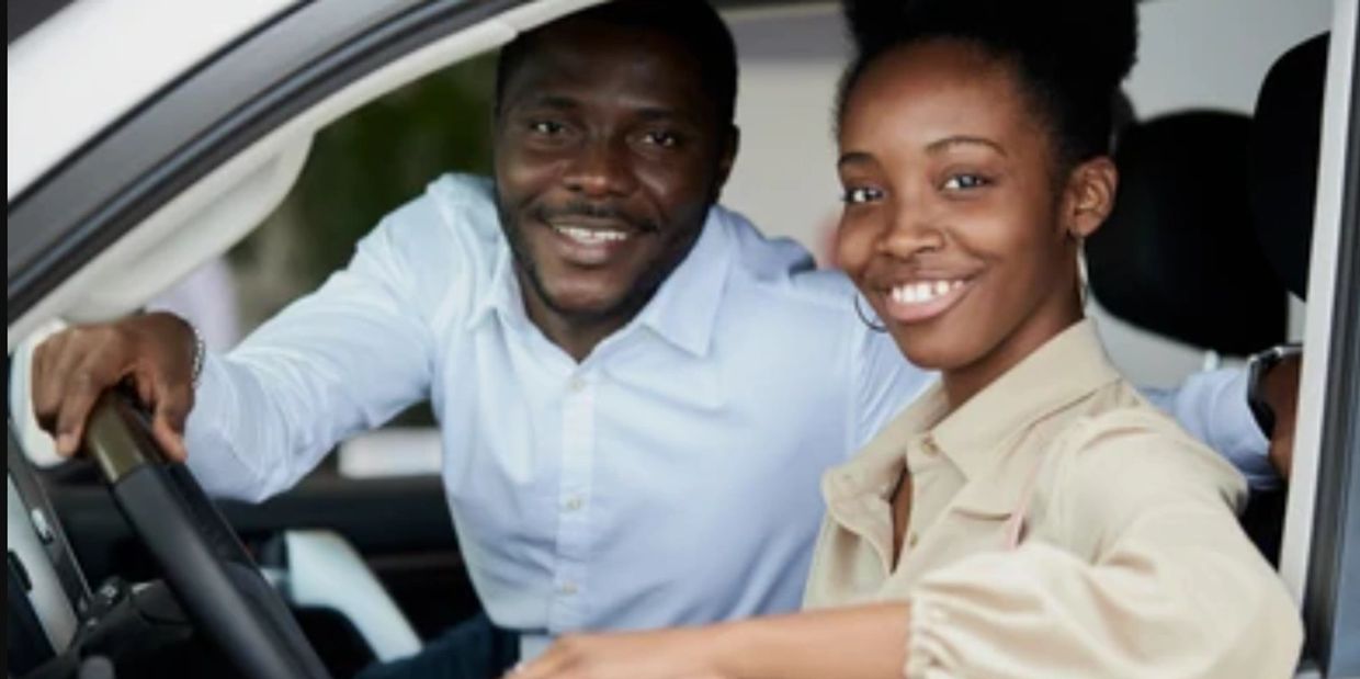 A driving instructor is pulled over smiling with his student.