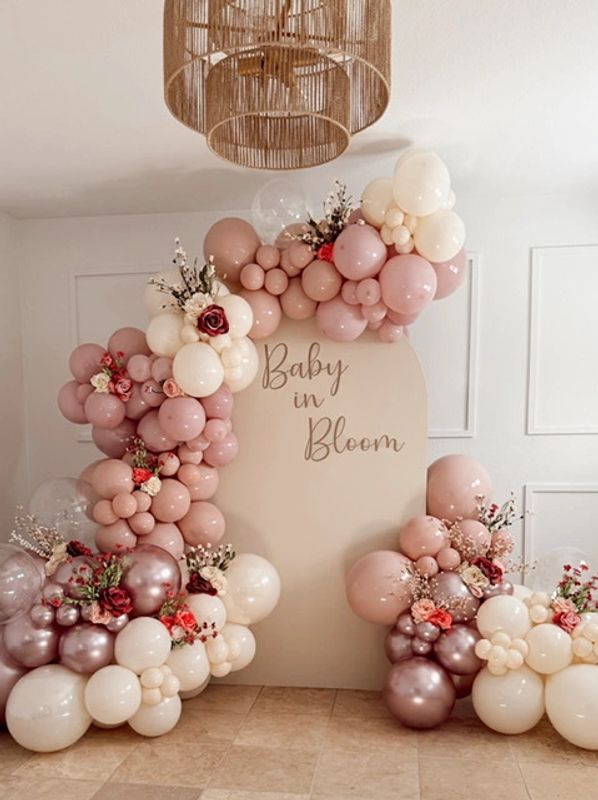 Baby in bloom backdrop with lush pink and white balloon garland and flower accents 
