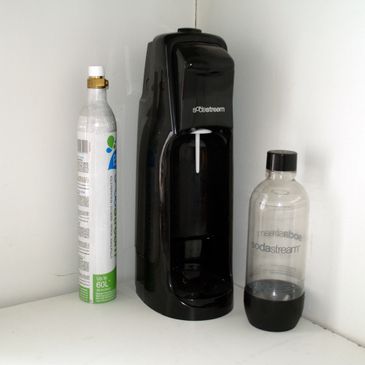 Black SodaStream machine with CO2 cylinder and plastic bottle.