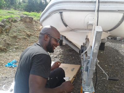 Man working on a boat trailer, smiling.