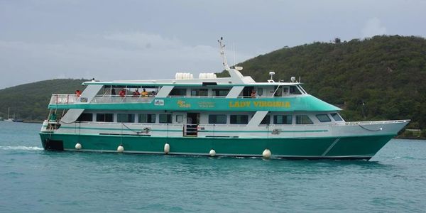 A large green and white passenger boat named Lady Virginia on calm water.