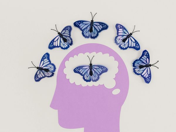 Purple head silhouette with blue butterflies inside and around it.