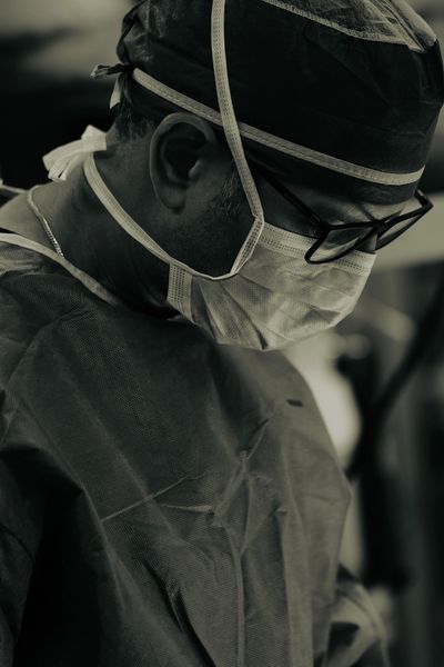 Surgeon focused during a medical procedure, wearing protective gear.
