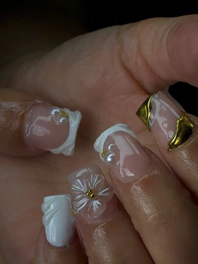 Elegant nails with 3D white flowers, pearls, and gold accents.