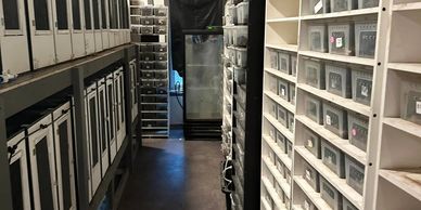 A storage room with shelves filled with labeled plastic containers and boxes.