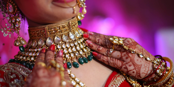 Close-up of a bride adorned with traditional Indian jewelry and mehndi on her hands.