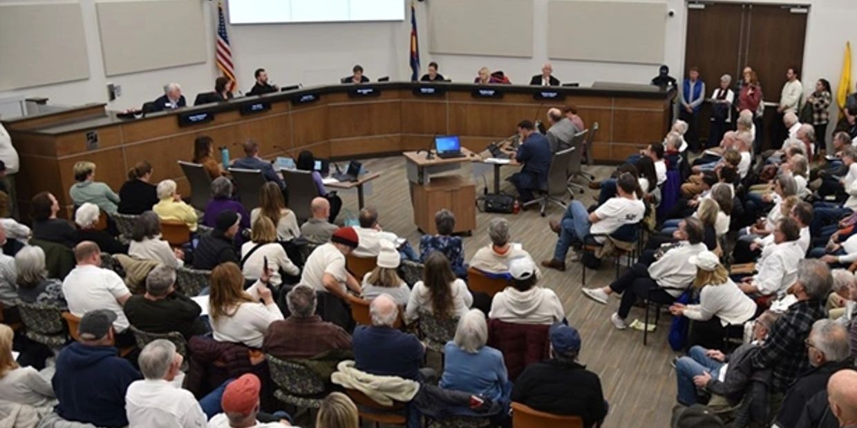 Large community meeting in a council chamber.