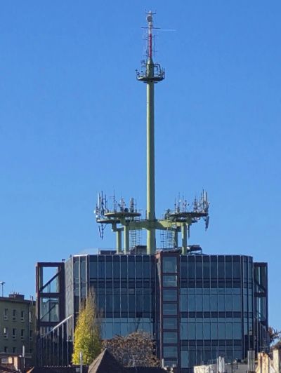 Tall communication antenna on a building roof.